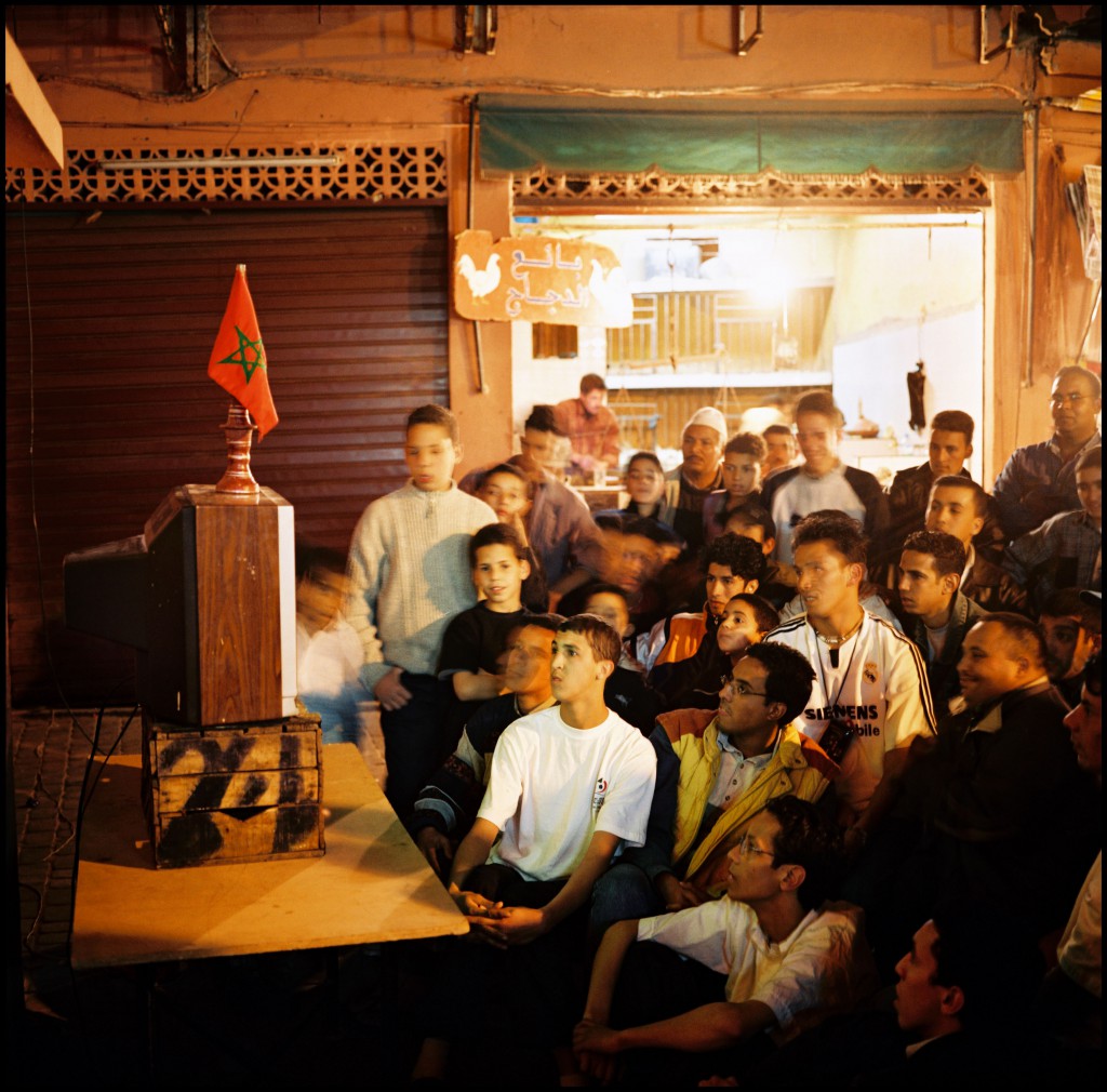 Medina, quartier de Bab Doukkala. Habitants du quartier regardant, sur une télévision installée dans la rue, la seconde demi-finale de la Coupe d'Afrique des Nations de football opposant le Maroc au Mali. Le Maroc vaincra par quatre buts à zero. Marrakech, Maroc 11/02/2004